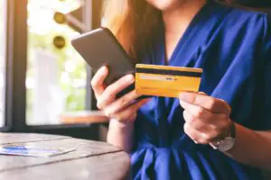 A woman looking at the phone while holding a credit card