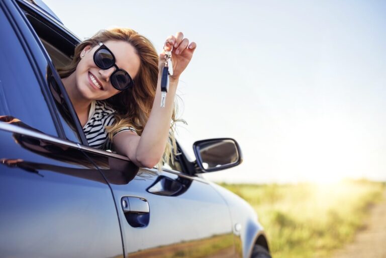 A woman leaning outside the car through the window while holding car keys