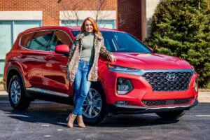 Woman leaning on a red SUV